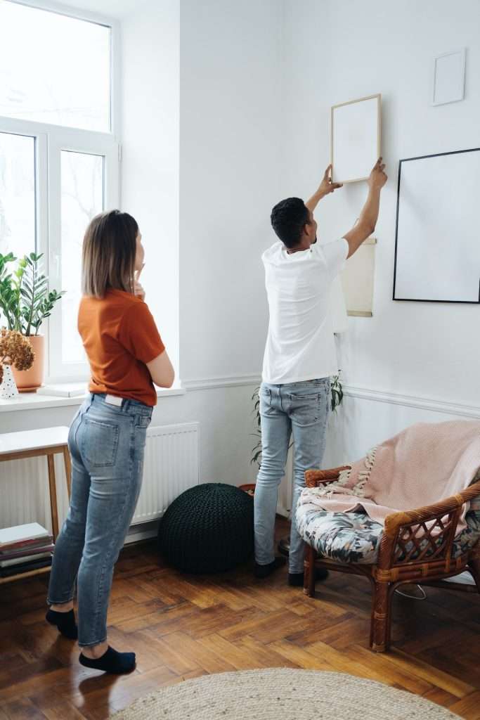 Mixed race ethnicity millennial couple holding frame admires painting or photo